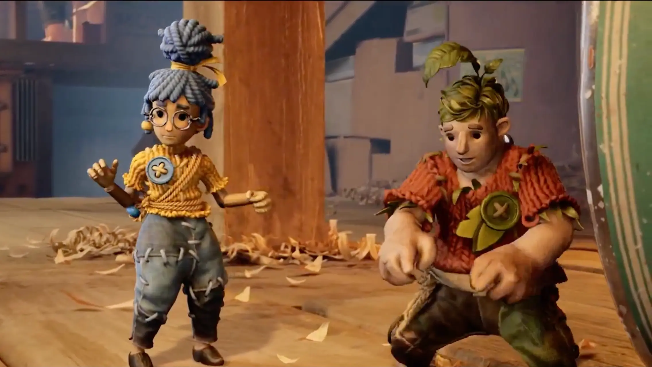 Cody and May trapped in their tiny doll bodies, looking utterly bewildered as they stand on a massive workbench.