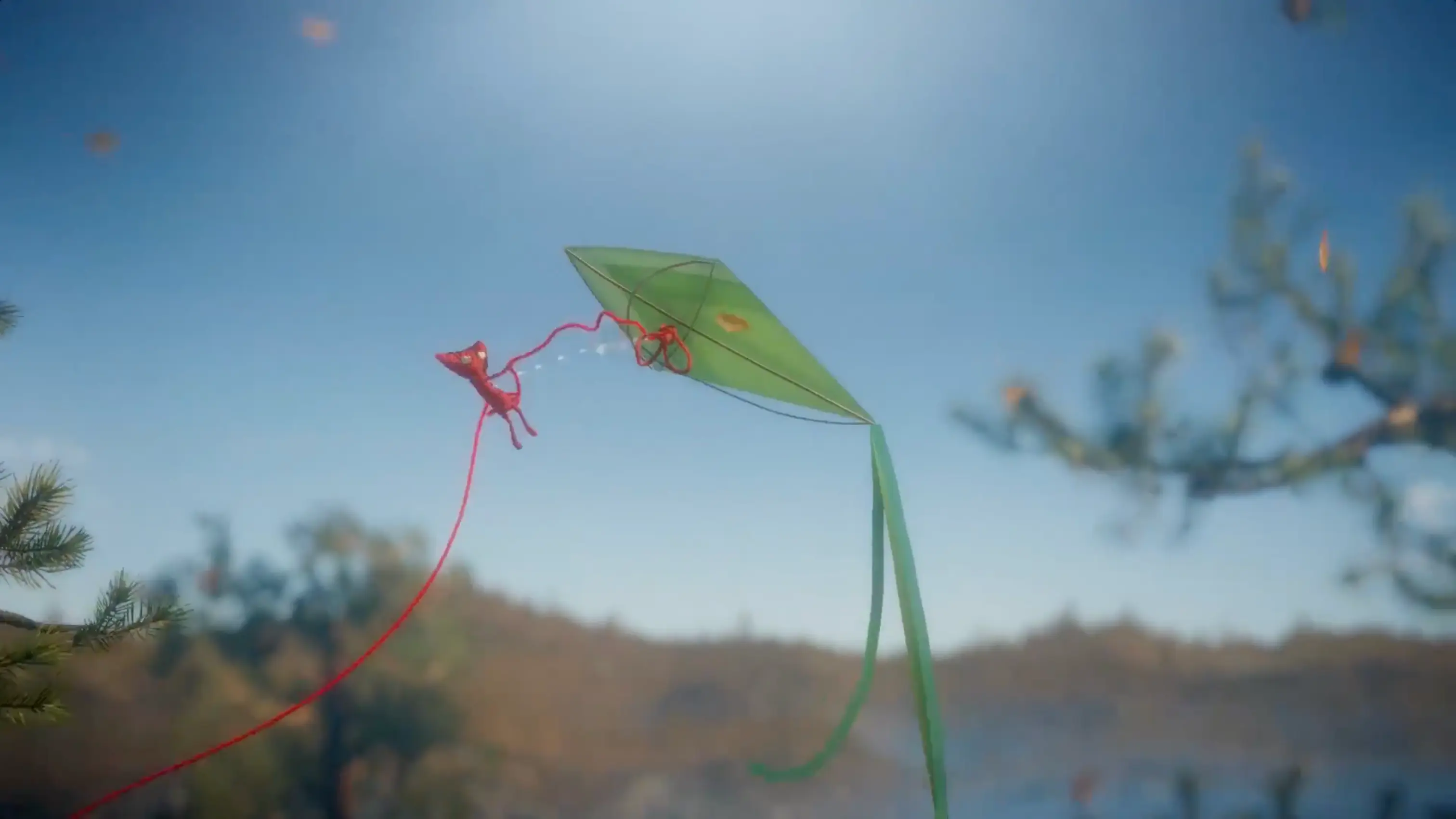 Yarny hanging onto the tail of a flying kite, soaring high above the trees.